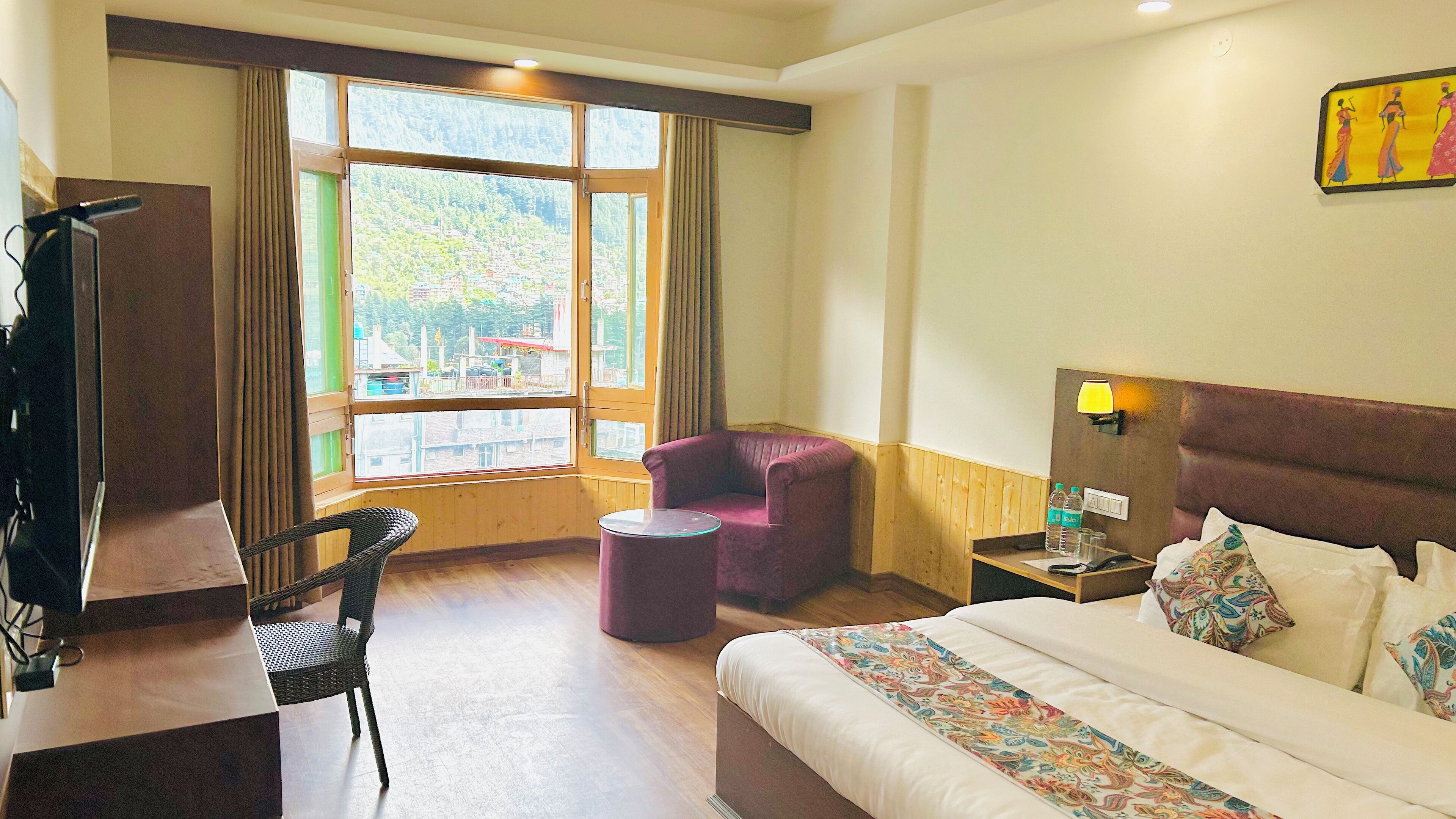 A hotel room with a bed, a desk, a chair, a small round table, and a window with curtains.