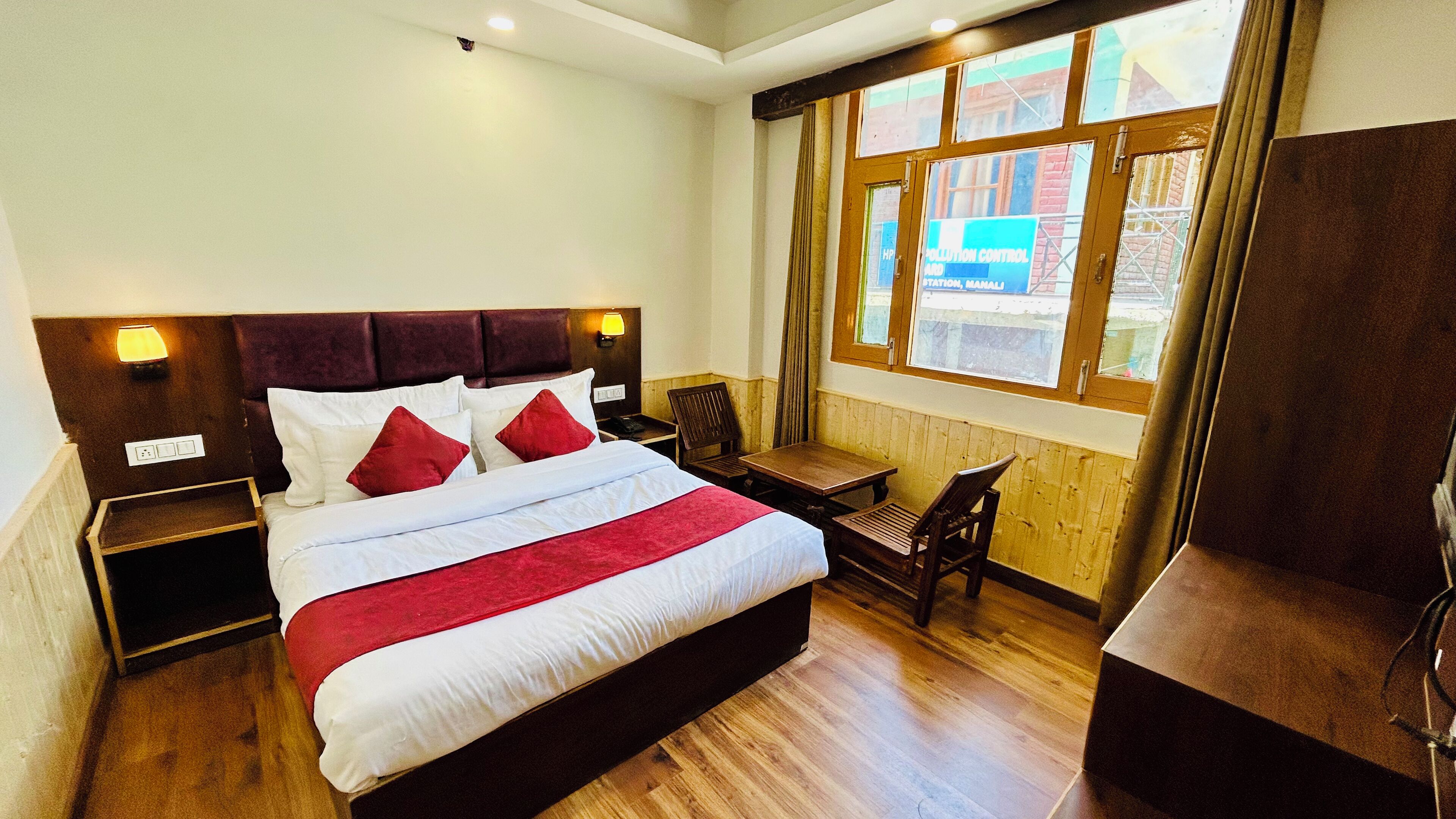 A hotel room with a large bed, bedside tables, a desk, and a window with a view of the outside.