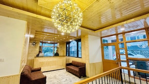 Un intérieur en bois comprenant un comptoir d’accueil, deux canapés et un grand lustre.