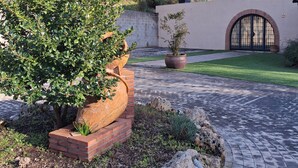 En anlagt have med en murstensrabat, en potteplante og en belagt sti.
