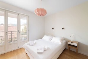 Een slaapkamer met een groot bed, een nachtkastje, een hanglamp en uitzicht door een schuifdeur.