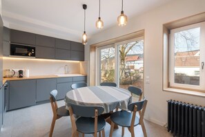 Een moderne keuken met een eethoek, met een groot raam, inbouwapparatuur en een tafel met stoelen.
