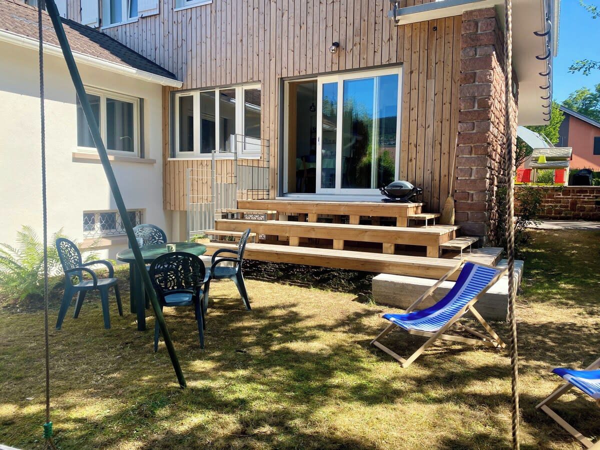 Une terrasse en bois avec un espace salon extérieur et un coin barbecue.