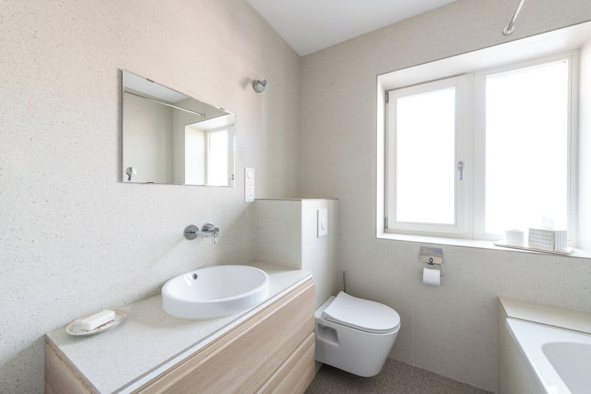 A modern bathroom with a sink, mirror, toilet, and bathtub.