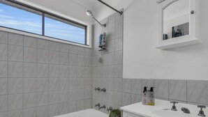 A modern bathroom with a bathtub, a shower, and a vanity with a mirror.