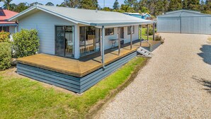 A modern, single-story house with a covered patio, a gravel driveway, and a small garden area.