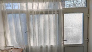 A kitchen with a wooden countertop, a white refrigerator, a window with sheer curtains, and a door with frosted glass. - Studio Breda Modern Furnishing space with a comfortable, 4min drive station. (Breda)