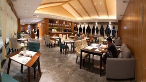 A spacious hotel lobby with multiple seating areas, including tables and chairs, and a bar area in the background. - LOTUS BLU HOTEL NAGA (Naga)