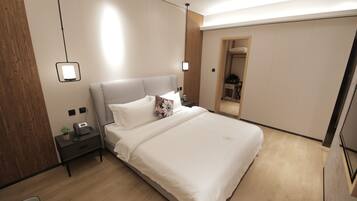 Quarto de hotel moderno com uma cama grande, mesas de cabeceira e um guarda-roupa.