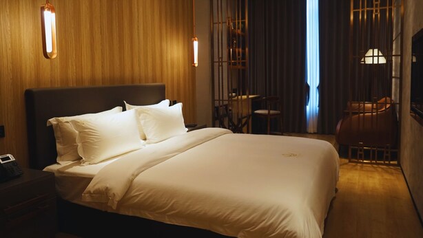 A hotel room with a large bed, bedside tables, a desk, and a chair. - LOTUS BLU HOTEL NAGA (Naga)