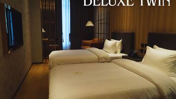 A hotel room with two beds, a TV, a desk, and a lamp.