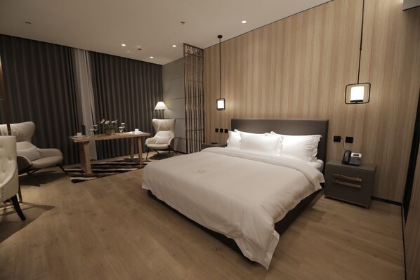 A modern hotel room with a large bed, a desk with chairs, and a phone on the nightstand.