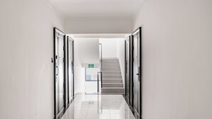 Un pasillo limpio y moderno con suelo de mármol, que conduce a una escalera y un letrero de salida de emergencia.