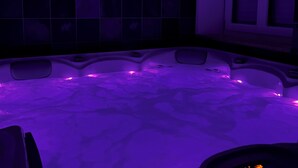 A spa bath with purple lighting, a tiled wall, and a cabinet. - Bed and breakfast with private Jacuzzi in secluded countryside setting. Relaxation guaranteed! (Fresnes)