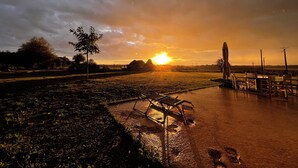 A sunset over a rural landscape with a field, a tree, and a table with chairs. - Bed and breakfast with private Jacuzzi in secluded countryside setting. Relaxation guaranteed! (Fresnes)