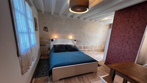 A bedroom with a bed, a nightstand, a table, and a patterned wall. - Bed and breakfast with private Jacuzzi in secluded countryside setting. Relaxation guaranteed! (Fresnes)