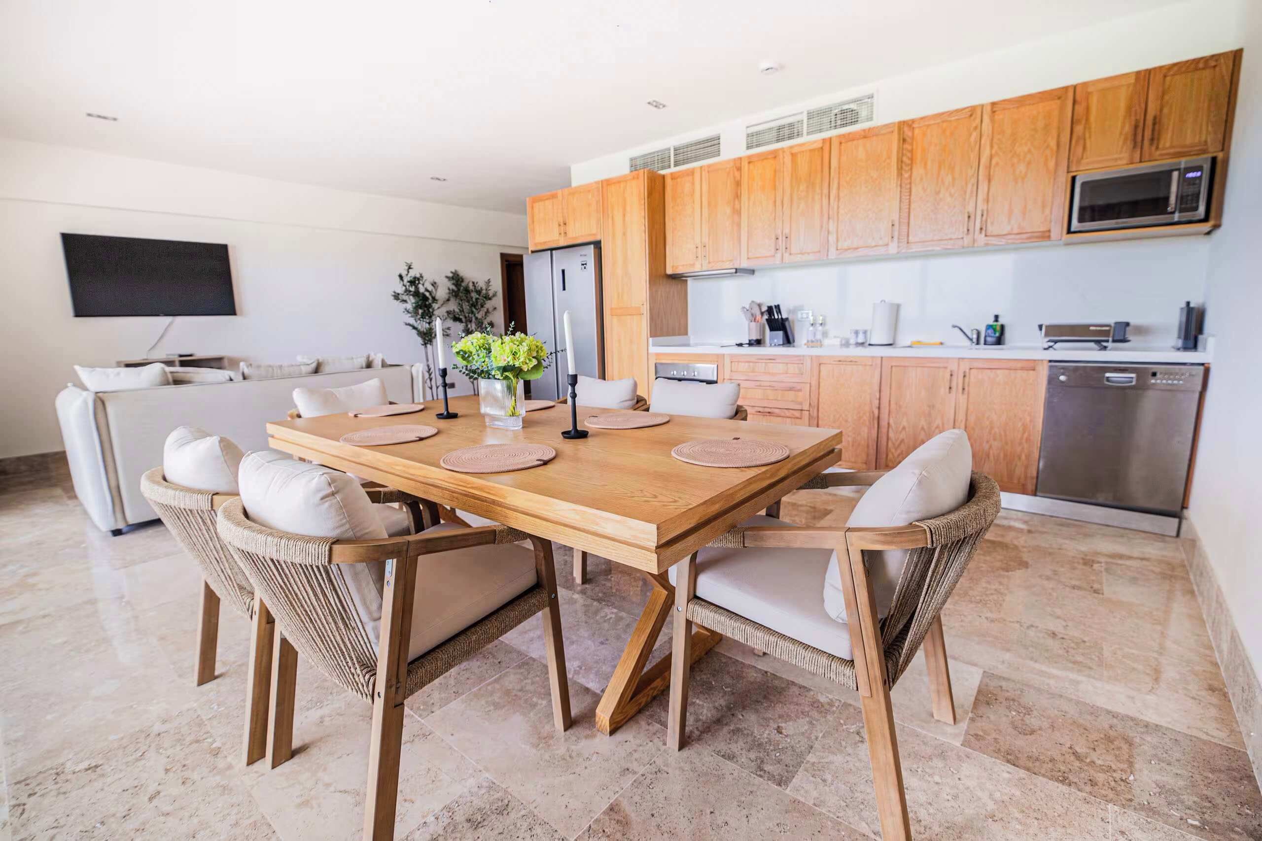 A modern kitchen with wooden cabinets, a dining table with chairs, and a built-in microwave.