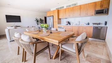 A modern kitchen with wooden cabinets, a dining table with chairs, and a built-in microwave.