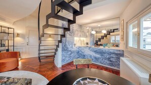 A modern interior with a curved staircase, a marble kitchen island, and a seating area with a round table.