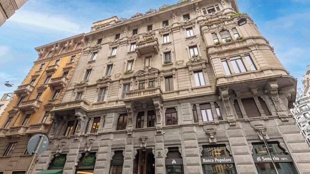A historic building with ornate architectural details, multiple balconies, and storefronts including a restaurant.