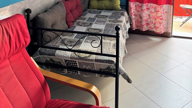 A room with a bed, a red chair, a blue wall, a framed picture, and a red curtain. - Apartment within walking distance of the Politeama Theater on Principe di Belmonte Street (Palermo)