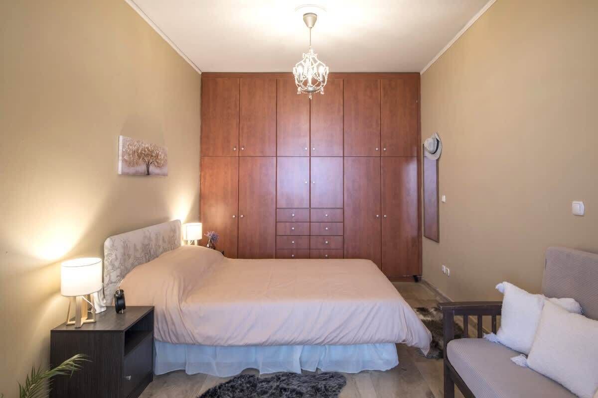 Une chambre à coucher avec un grand lit, une armoire, une table de chevet, une lampe et un lustre.