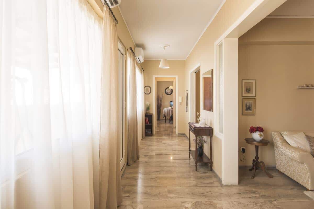 A hallway with a marble floor, a sofa, and a small table with flowers.