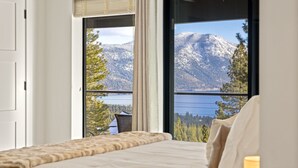 Une chambre dotée d’une grande fenêtre donnant sur les montagnes et un lac.