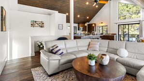 Un salon spacieux avec un grand canapé d’angle, une table basse en bois et un ventilateur de plafond.