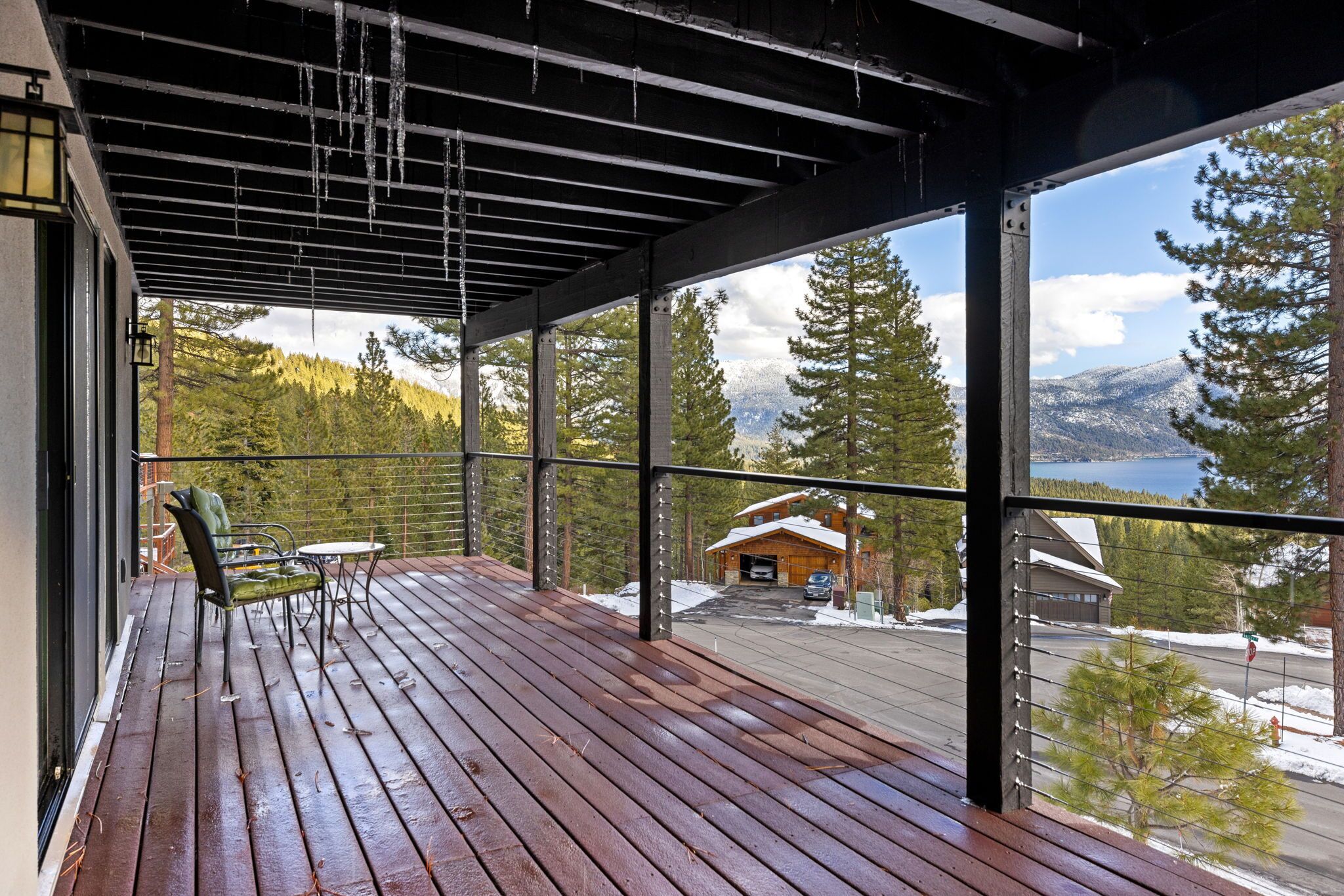 A wooden deck with a view of a cabin and mountains.