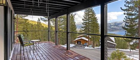 A wooden deck with a view of a cabin and mountains.