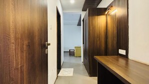 A hallway with wooden doors, a bench, and a light fixture on the wall. - MOUNTAIN BREEZE RESORT (Mahabaleshwar)