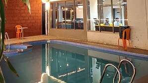 A hotel with a pool area, a sign reading "Mountain Breeze," and a brick wall. - MOUNTAIN BREEZE RESORT (Mahabaleshwar)