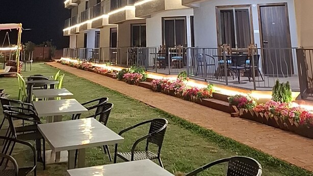 A multi-story building with outdoor seating and a well-lit balcony area. - MOUNTAIN BREEZE RESORT (Mahabaleshwar)