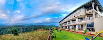 A hotel with multiple balconies, a well-maintained lawn, and a view of the surrounding landscape.