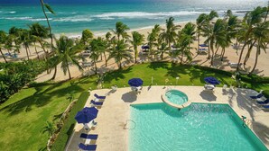 Un complexe hôtelier doté d’une piscine, d’une plage et de palmiers.