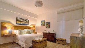 Une chambre à coucher comprenant un lit, des tables de chevet, une commode et des œuvres d’art murales.