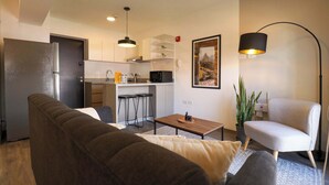 Un espace de vie compact comprenant un canapé, une table à manger, un coin cuisine et une chaise.
