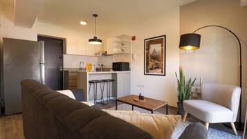Un espacio habitable compacto con sofá, mesa de comedor, zona de cocina y una silla.