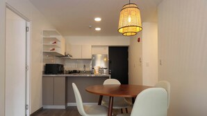 A compact kitchen with white cabinets, a wooden dining table, and a hanging light fixture. - w* | Modern 2BR in Historic Cusco w/ Balcony (Cusco)