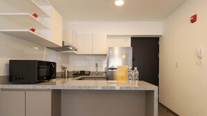 A modern kitchen with a microwave, sink, and stainless steel refrigerator. - w* | Modern 2BR in Historic Cusco w/ Balcony (Cusco)