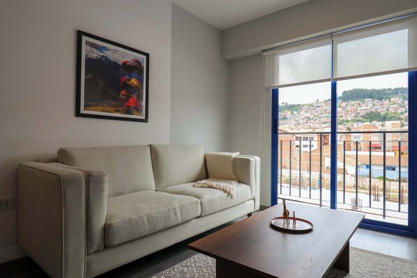 Ein Wohnzimmer mit einer Couch, einem Couchtisch und einem großen Fenster mit Blick auf die Stadt.
