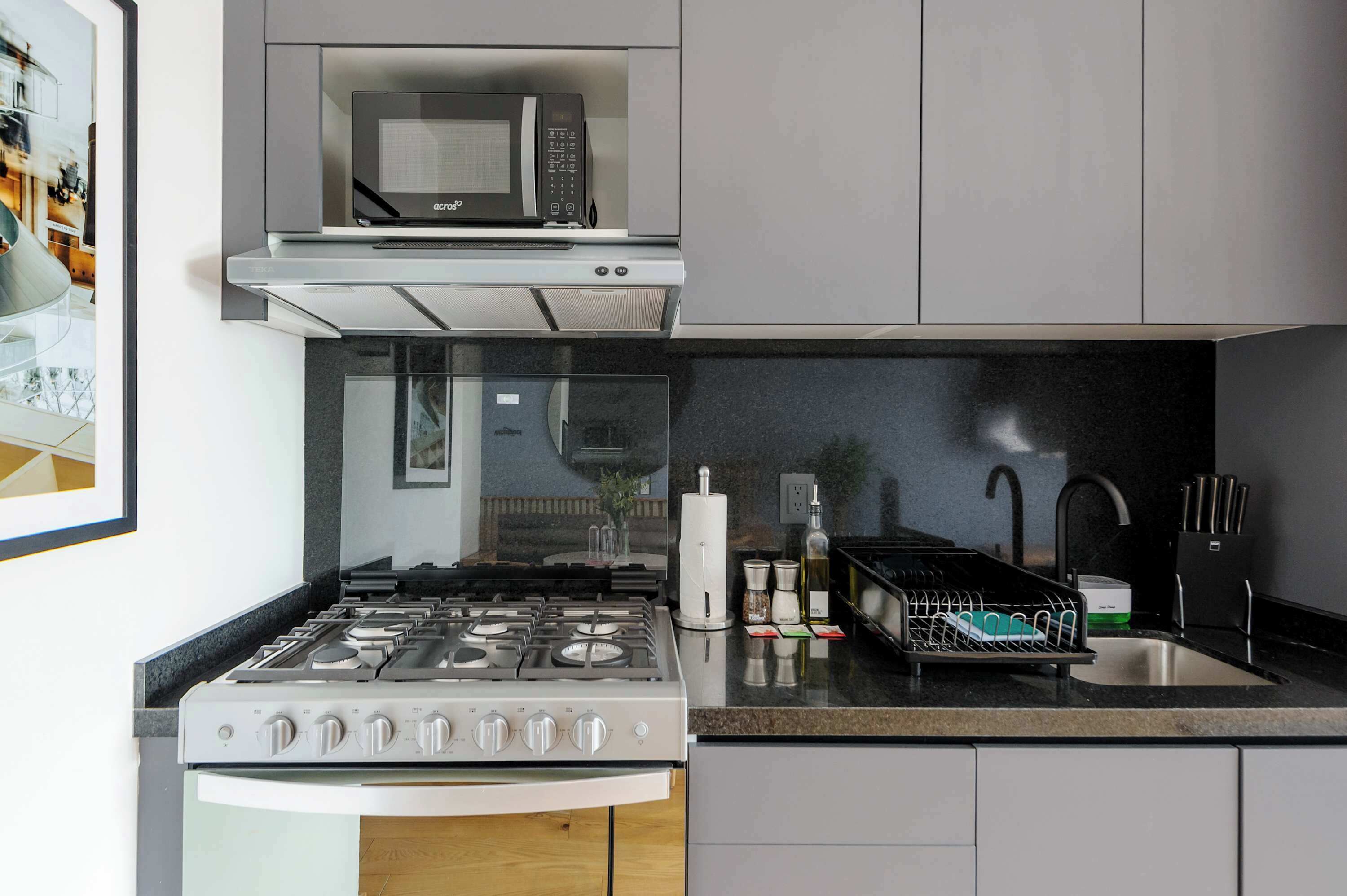 A modern kitchen with a gas stove, a microwave, and a stainless steel sink.