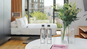 A modern hotel room with a bed, a round table with a vase of plants, and two bottles labeled "PODOMANYA". - w* | Wonderful Loft w/ Balcony in Roma Norte (Ciudad de México)