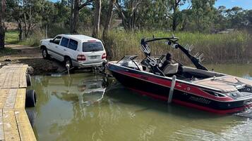 A boat docked at a wooden pier with a white vehicle nearby.