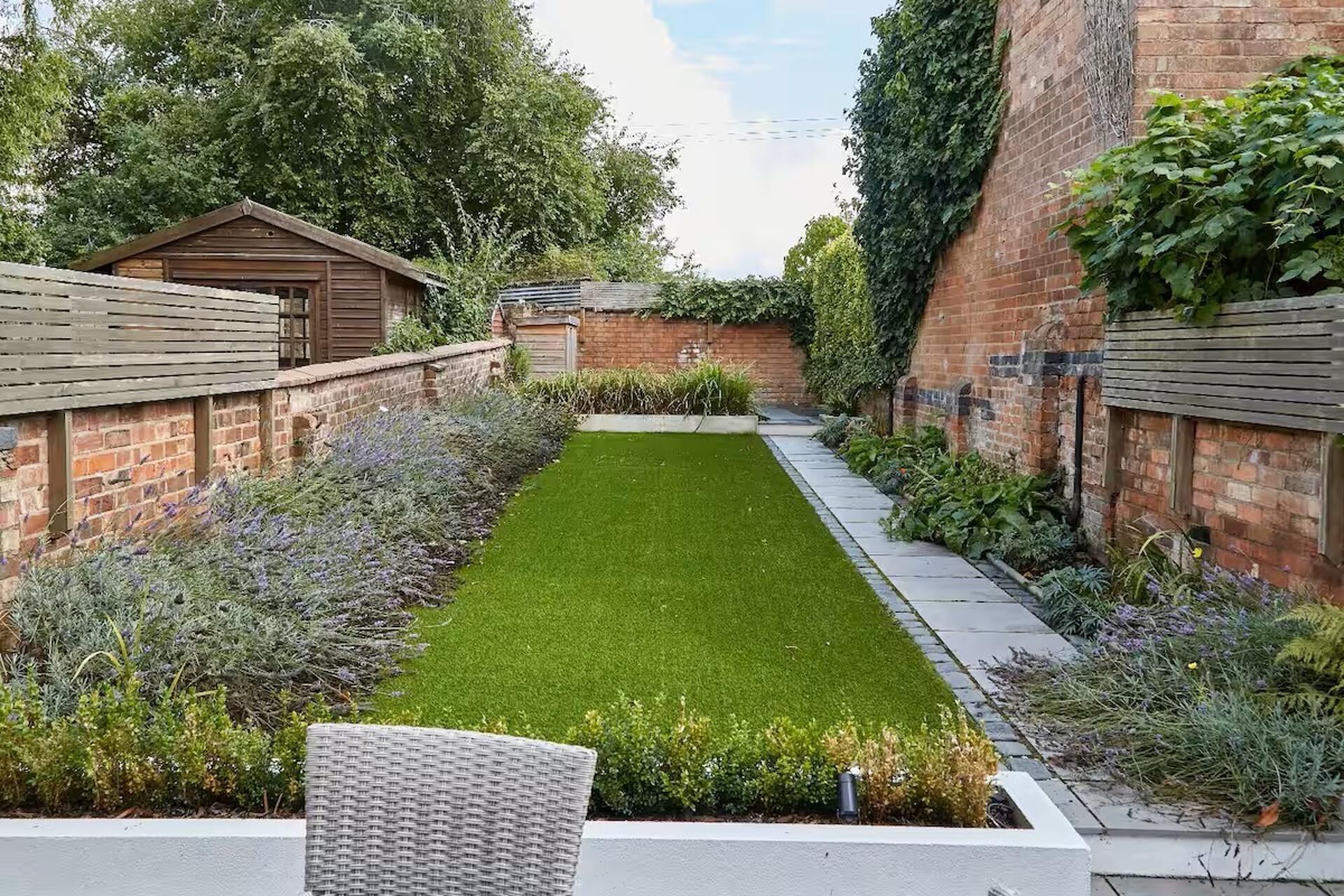 A well-maintained garden with a lawn, a pathway, and a wooden fence.