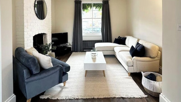 Un salon moderne avec une cheminée, un canapé blanc, un fauteuil foncé et une table basse.