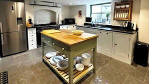 Une cuisine moderne dotée d’appareils électroménagers en acier inoxydable, d’un îlot central en bois avec rangements et offrant une vue sur l’extérieur.