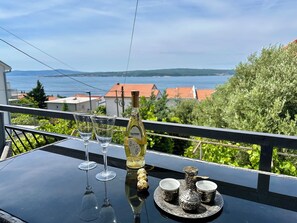 A balcony with a table set for two, featuring a bottle of Chardonnay, two wine glasses, and a silver tea set. - Apartman Queen (Dramalj)