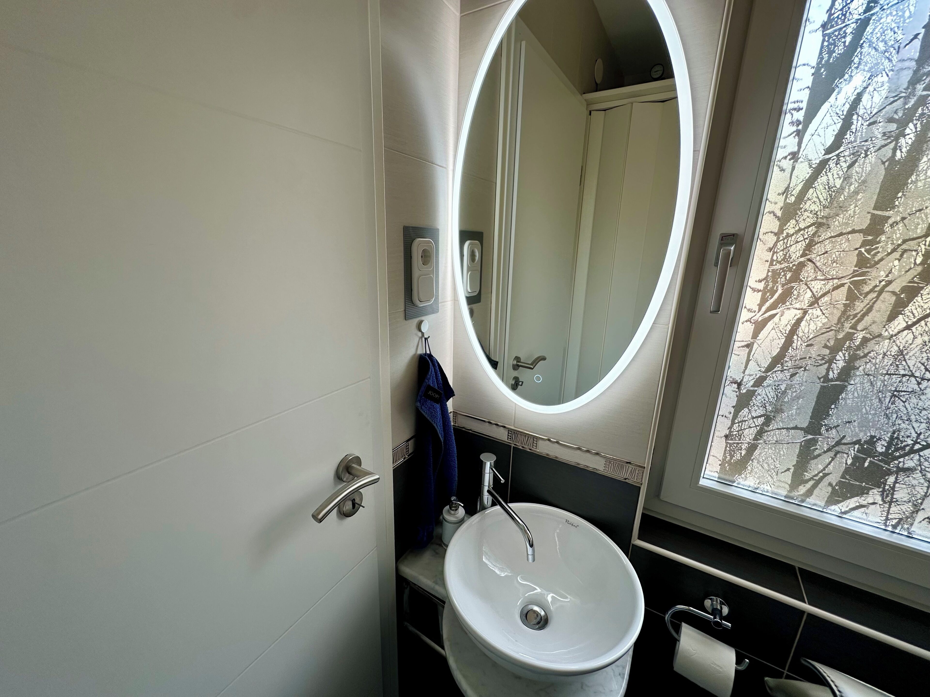 A bathroom with a white sink, a mirror, and a window.